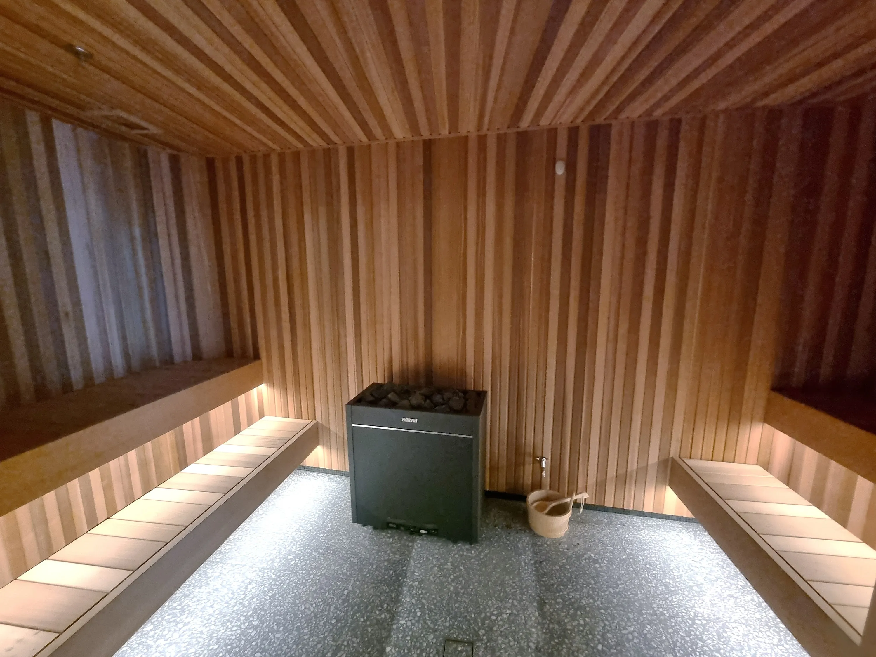 Commercial timber sauna with benches on both sides of a central heater
